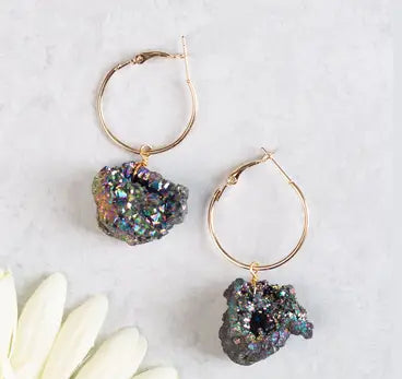 Gold hoop earrings with natural rock-like charms on a light background