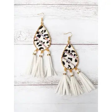 Pair of earrings with leopard print and white tassel design on a light wooden background