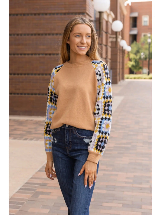 Patchwork Sleeve Sweater. Featuring a warm camel-toned body and vibrant patchwork-patterned sleeves.