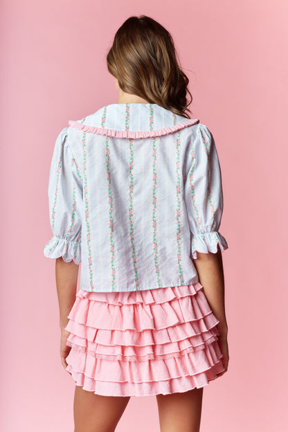  Sailor-Collar Cropped Blouse blends vintage charm with playful femininity. Designed with a relaxed fit and cropped length, this blouse features a sailor-style collar adorned with ruffle trim and delicate floral embroidery on a striped fabric. 