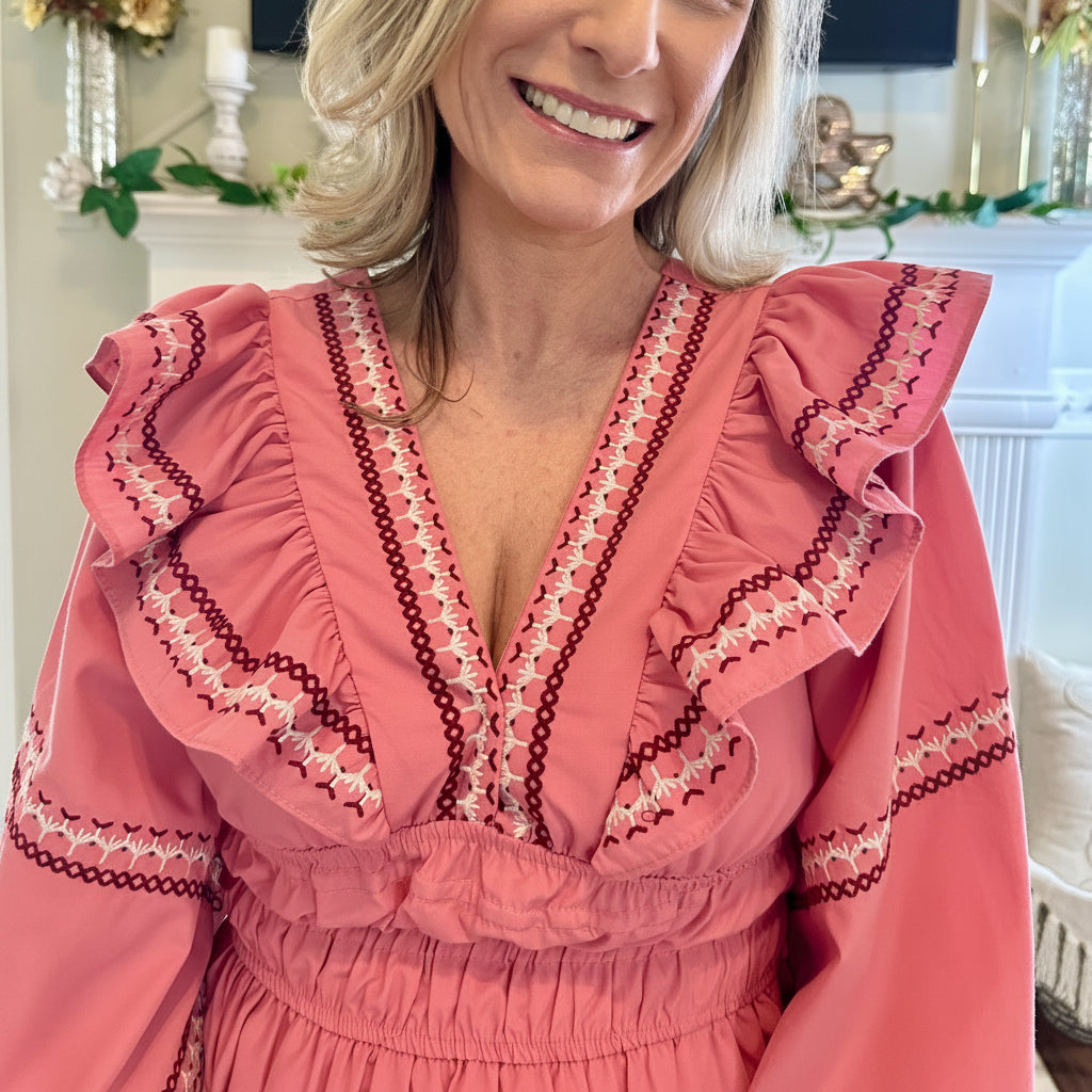 Woman wearing a pink dress with intricate detailing in a decorated room.