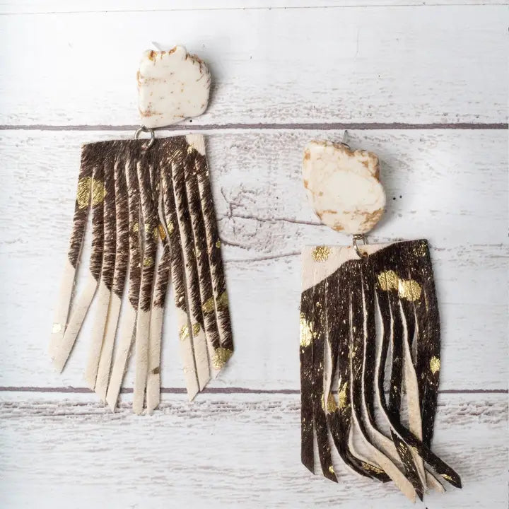 Pair of earrings with long, thin, layered design on a light wooden surface
