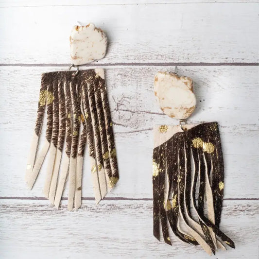 Pair of earrings with long, thin, layered design on a light wooden surface