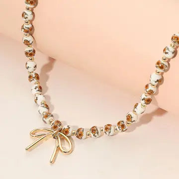 Bracelet with gold bow charm on a pink background