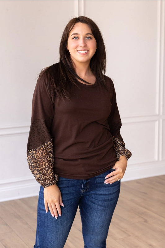 Leopard Sleeve Top is a stylish and versatile piece that adds a touch of boldness to your everyday look. Featuring a relaxed fit, this top stands out with its solid body and contrasting leopard-print sleeves with eyelet detailing.