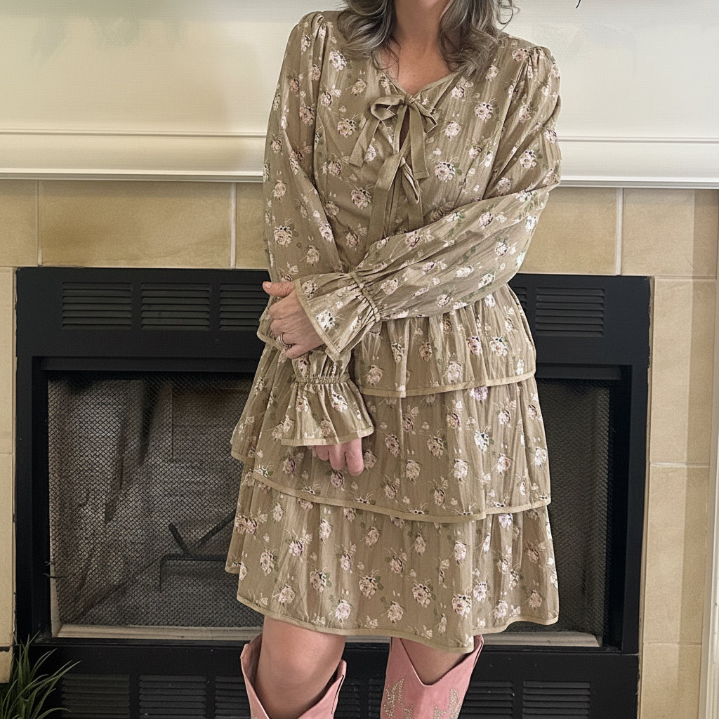 Woman in a patterned dress standing in a living room with a television and decorative items.