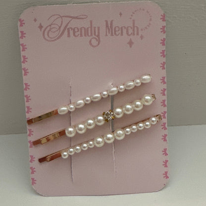 Three pearl-barrel hair pins with rose gold metal and a small rhinestone accent, displayed on a pink 'Trendy Merch' backing card against a neutral gray background.