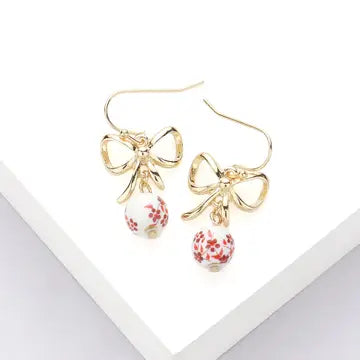 Gold bow-shaped earrings with floral drops on a white background