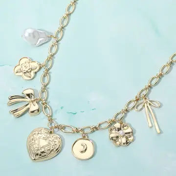 Gold charm bracelet with various charms on a light blue background