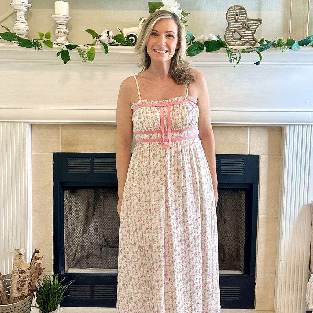 Woman in a floral dress standing in a living room with a fireplace.