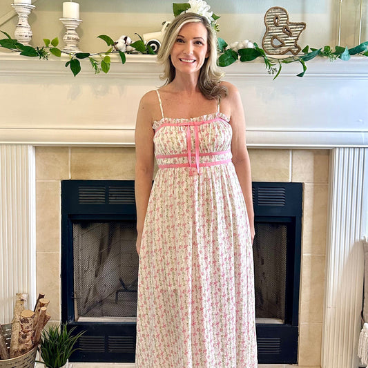 Woman in a floral dress standing in a living room with a fireplace.