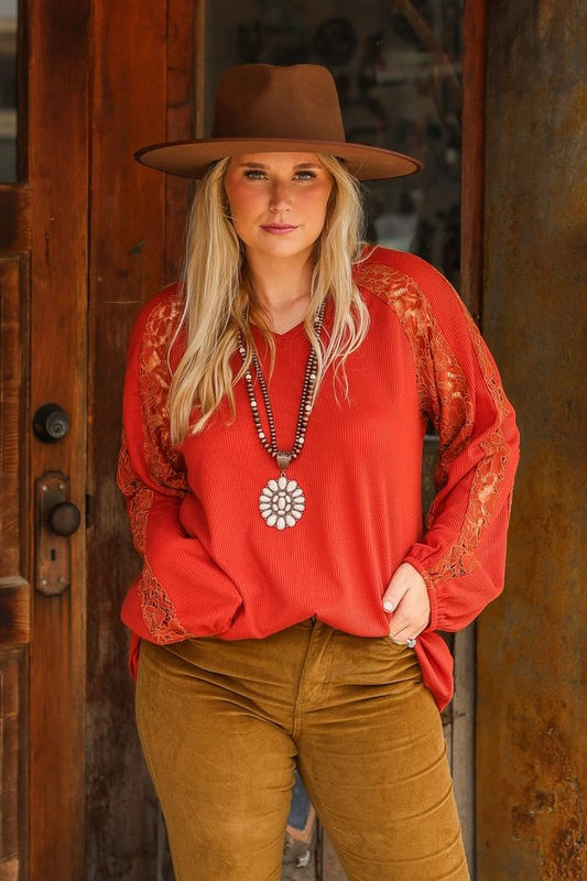  Rust Lace Sleeve V-Neck Top is a perfect balance of casual elegance and comfort. Designed with a relaxed fit and some stretch, this top features a flattering V-neckline and intricate lace inserts on the sleeves.