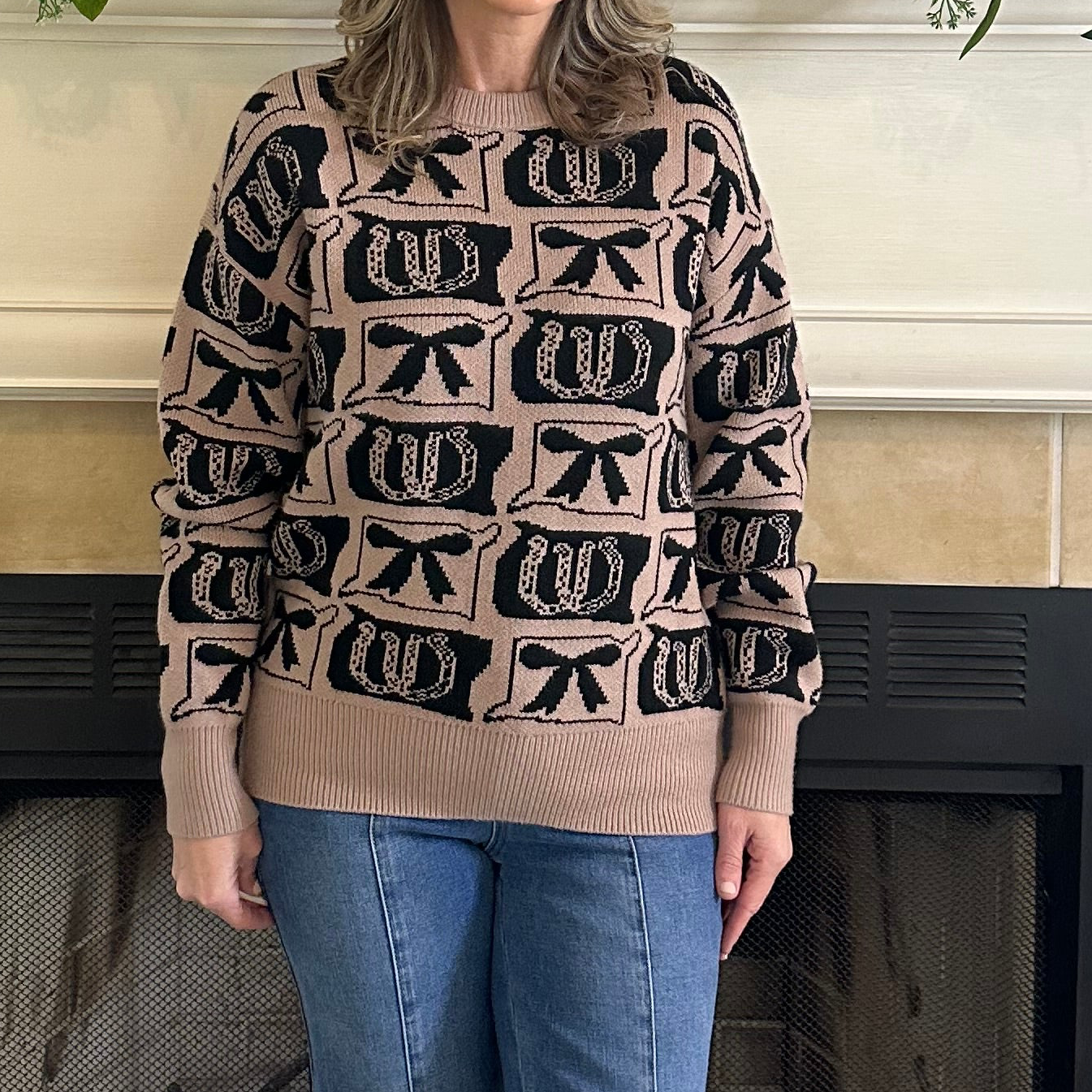 Person wearing a patterned sweater standing in front of a fireplace.