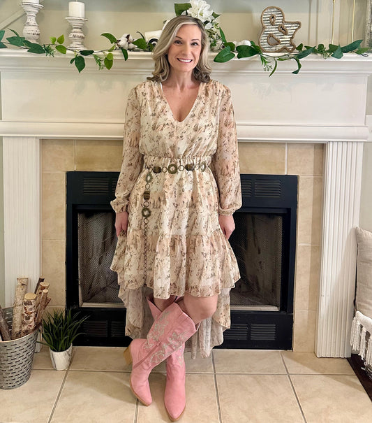Woman in a floral dress and pink boots standing in front of a decorated fireplace.
