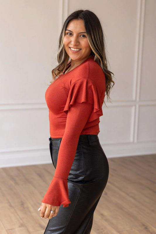 Rust  Ruffle Bodysuit, featuring a sleek, shimmering black fabric that perfectly balances boldness and grace. The cascading ruffle sleeves and flared cuffs create a dramatic silhouette. 
