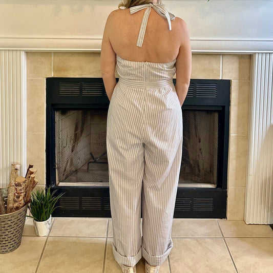 Woman in a white striped jumpsuit standing in front of a decorated fireplace.