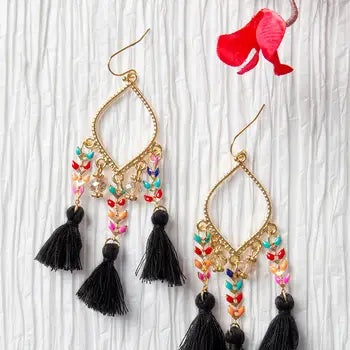 Colorful beaded earrings with tassels on a textured white background