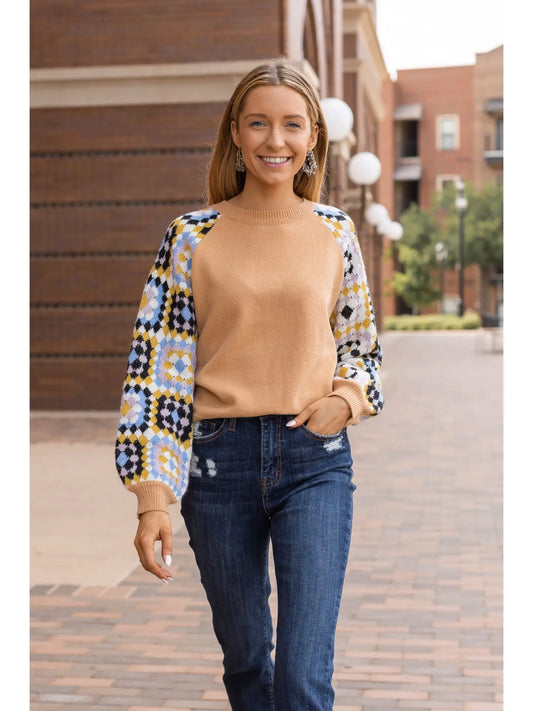 Patchwork Sleeve Sweater. Featuring a warm camel-toned body and vibrant patchwork-patterned sleeves.