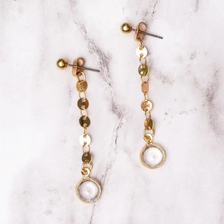 Gold and clear lbeaded earrings on a marble surface