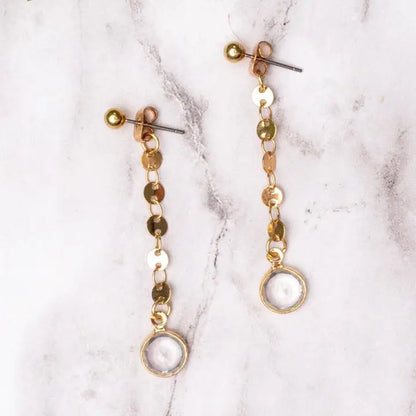 Gold and clear lbeaded earrings on a marble surface