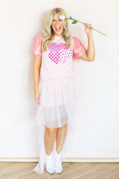 Sequin Sleeve Top is a playful and chic piece that stands out in any wardrobe. Featuring dazzling sequin-lined sleeves and a bold heart graphic.