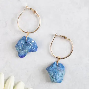 Gold hoop earrings with blue stone accents on a light background