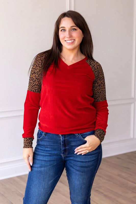  Red Velvet Top is a bold and stylish choice for any wardrobe. Featuring a luxurious red velvet body paired with leopard print accents on the sleeves and cuffs.