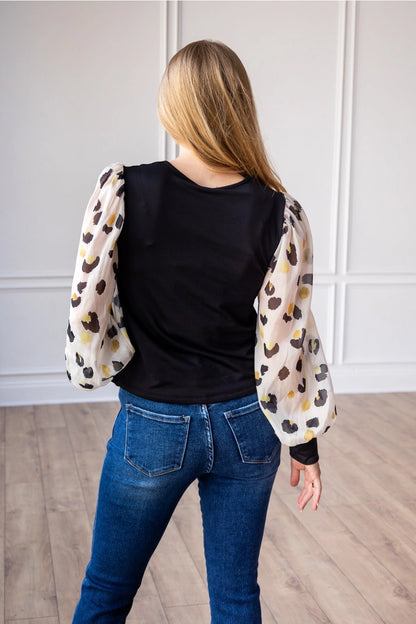 Leopard Sleeve Top is a stylish blend of simplicity and boldness. Featuring sheer leopard-print puff sleeves and a sleek solid bodice.