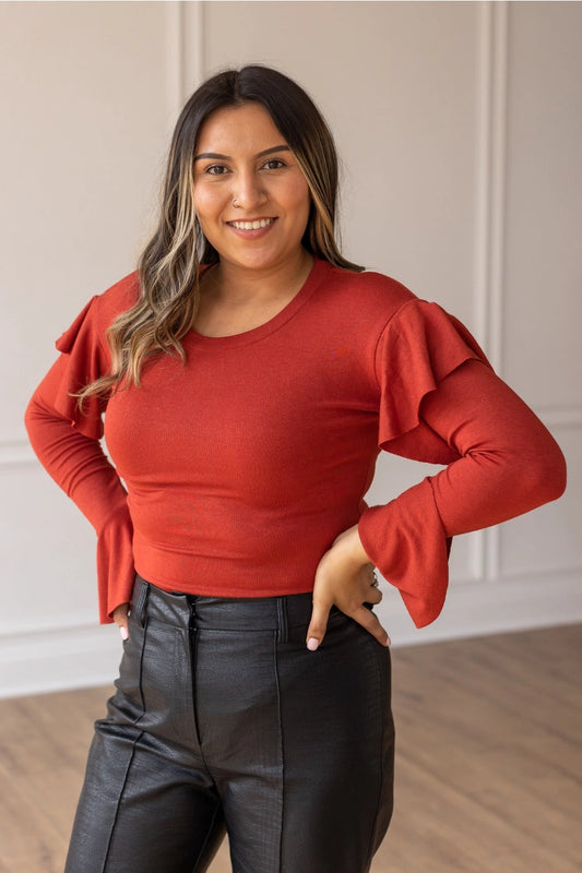 Rust  Ruffle Bodysuit, featuring a sleek, shimmering black fabric that perfectly balances boldness and grace. The cascading ruffle sleeves and flared cuffs create a dramatic silhouette. 