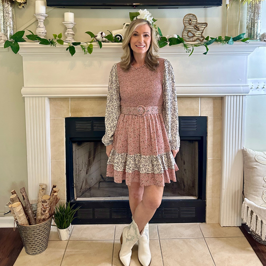 Woman in a floral dress standing in a living room with a fireplace.