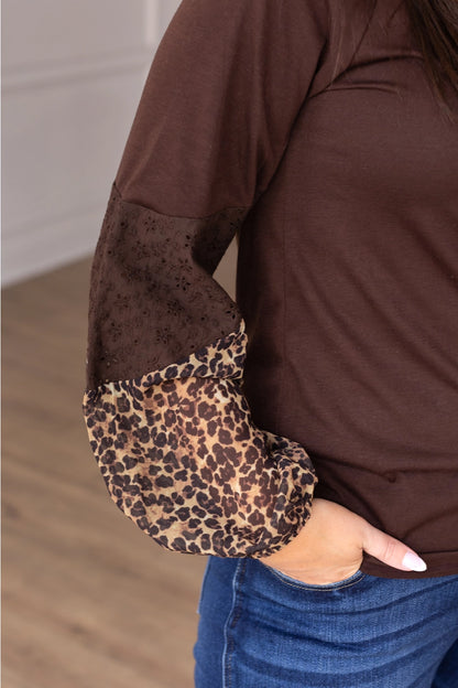 Leopard Sleeve Top is a stylish and versatile piece that adds a touch of boldness to your everyday look. Featuring a relaxed fit, this top stands out with its solid body and contrasting leopard-print sleeves with eyelet detailing.