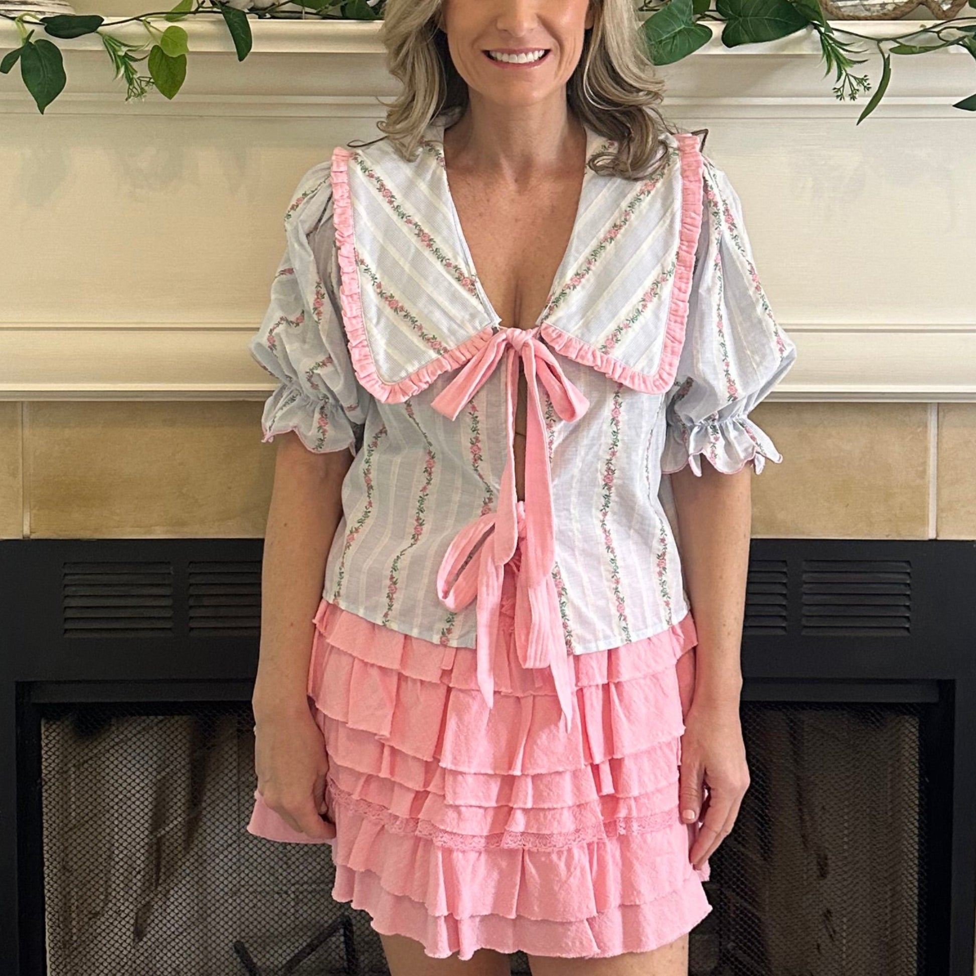 Woman in a pink dress standing in a room with decorative elements.