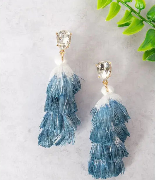 Blue and white feathered earrings on a light gray background. 