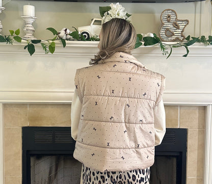 Person wearing a beige quilted jacket and leopard print pants standing in a living room.