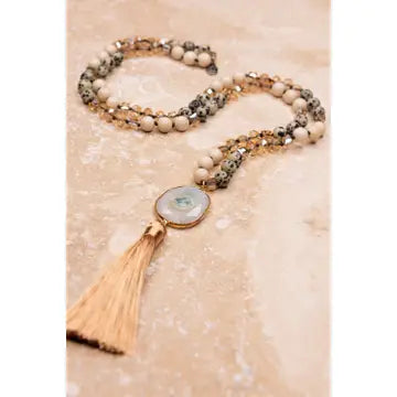 Necklace with beads and tassel on a textured surface