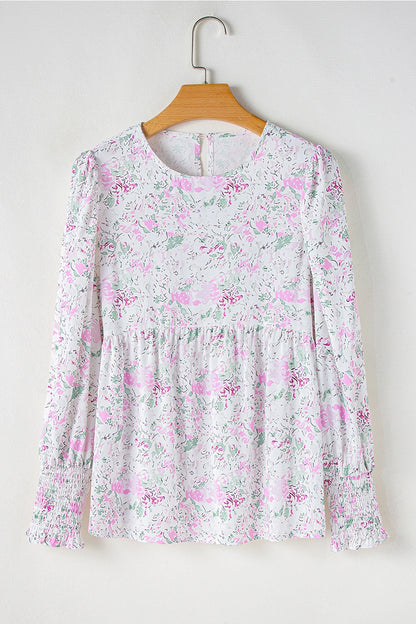 Floral Print Blouse. This blouse features a charming floral print in soft, pastel tones. The design includes a flattering V-neckline, long puffed sleeves with smocked cuffs, and a relaxed, flowy fit.
