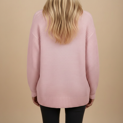 Person wearing a pink sweater against a beige background