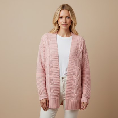 Woman wearing a pink cardigan over a white shirt and pants on a beige background