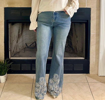 Person wearing blue jeans with decorative cuffs in front of a fireplace.