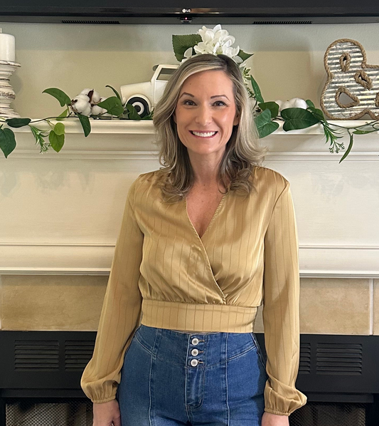 Woman standing in front of a decorated fireplace with festive elements.