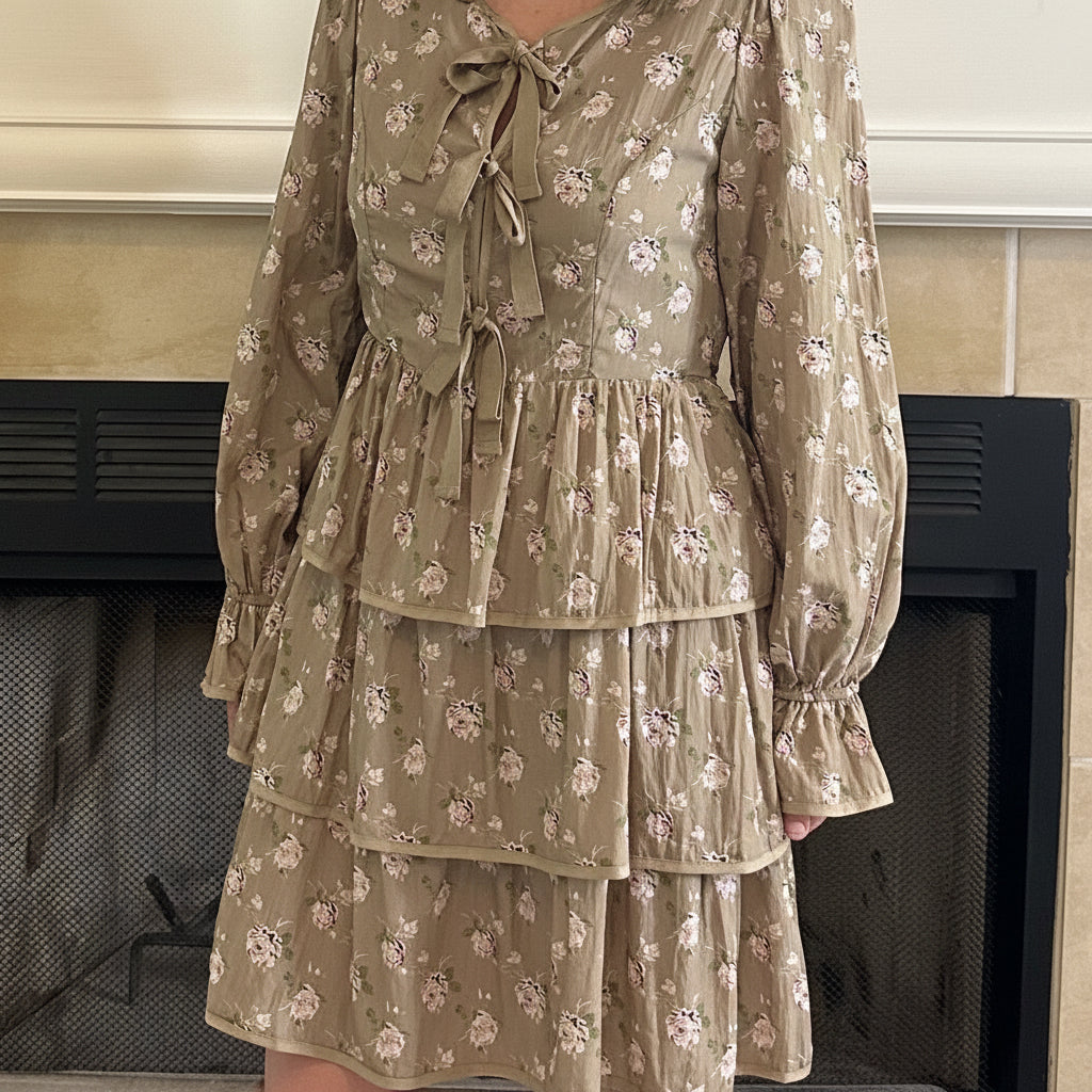 Woman in a patterned dress standing in a living room with a television and fireplace.