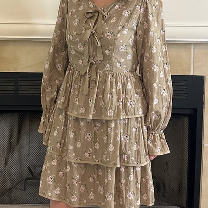 Woman in a patterned dress standing in a living room with a television and fireplace.