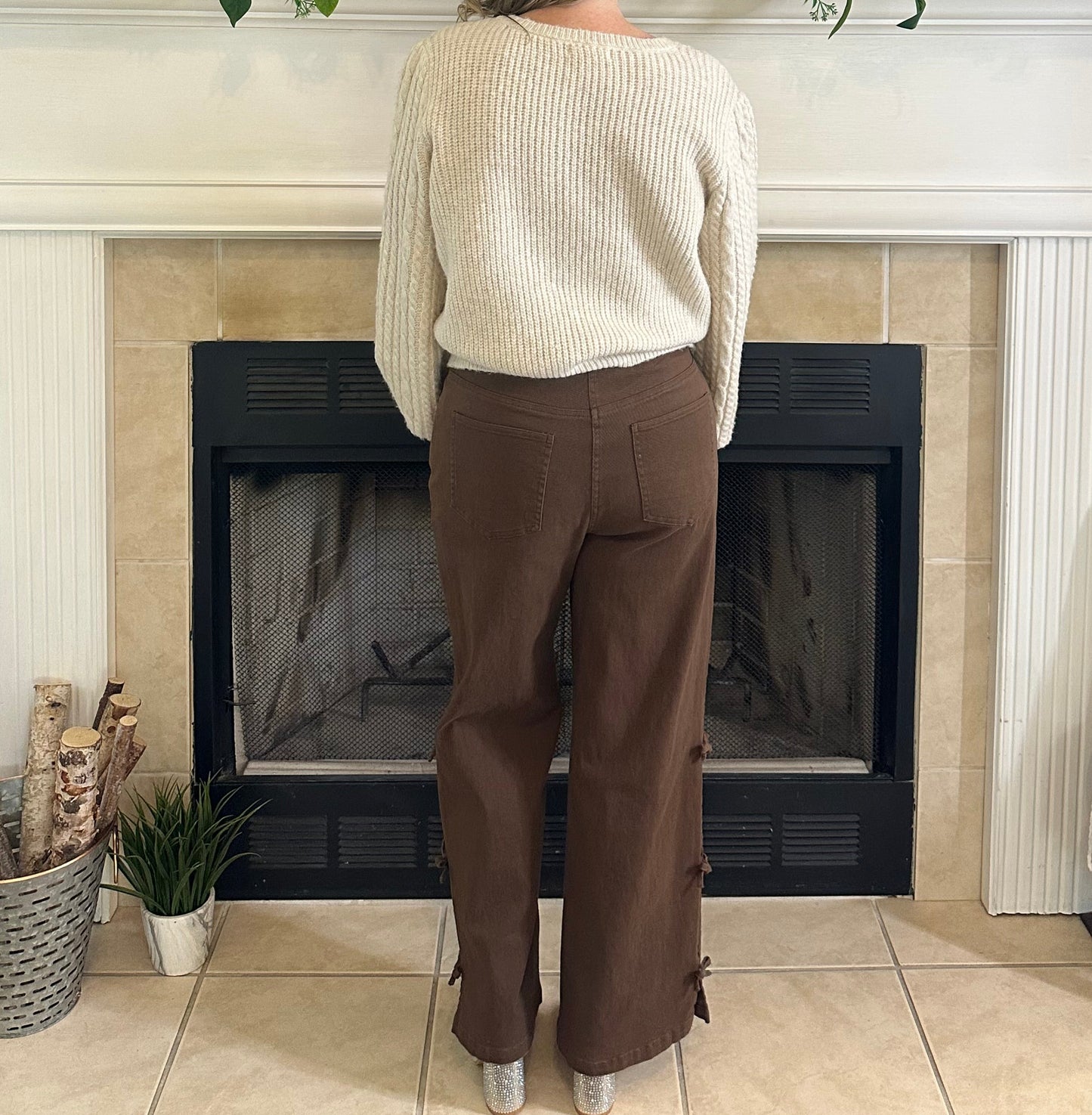 Person standing in a living room with a television, fireplace, and decorative items.