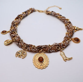 Gold necklace with charms on a light gray background