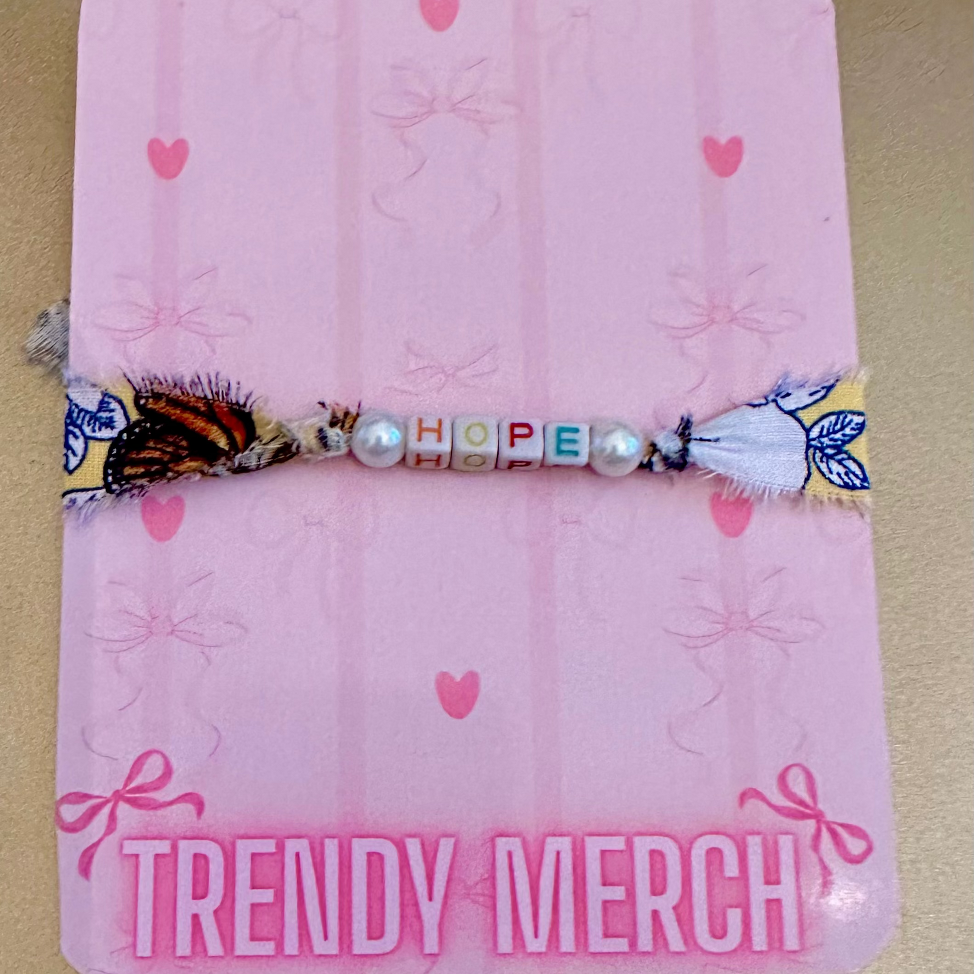 Pink fabric item with 'TRENDY MERCH' text and decorative elements on a beige background