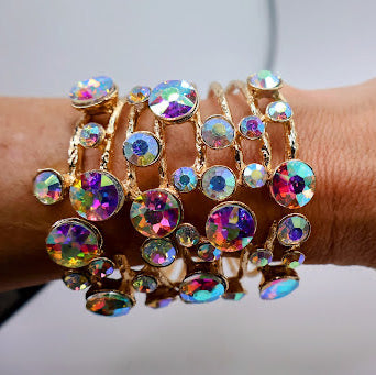 Multicolored gemstone bracelets on a wrist against a neutral background