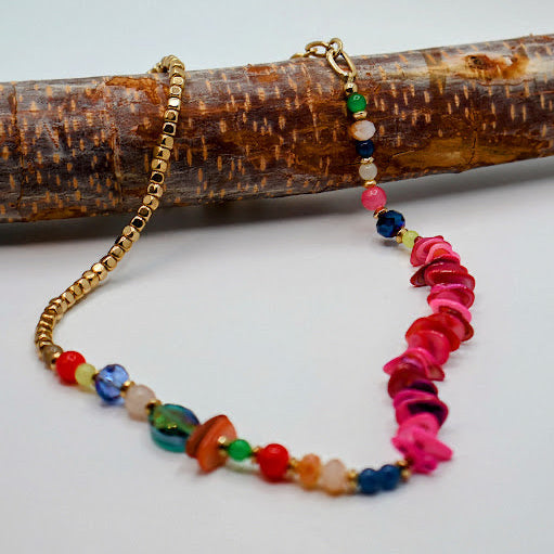 Colorful beaded necklace with gold chain on a wooden branch
