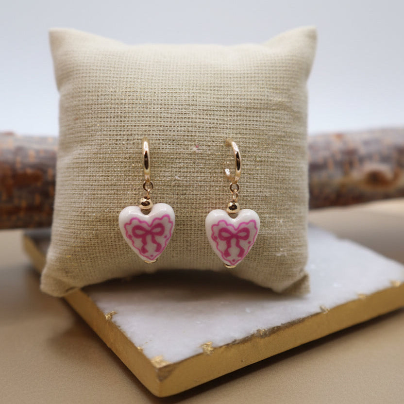Heart-shaped earrings with pink bows.