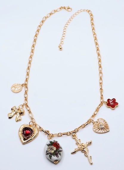  Vintage Charm Necklace. Featuring a gold-tone chain adorned with an exquisite collection of charms, including a rose-adorned heart, a dainty bow, a floral oval pendant, and a radiant cross.