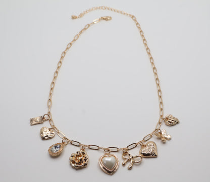  Charm Necklace.  Featuring a delicate gold-tone chain adorned with an array of feminine charms, including a pearl heart, a dainty bow, sparkling crystals, and floral motifs.